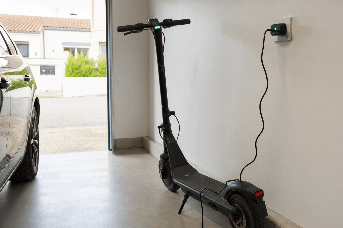 Trottinette électrique posée contre un mur, en charge, avec l'écran affichant le niveau de batterie