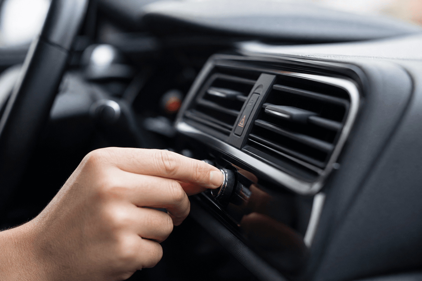 Main réglant la molette de climatisation près des aérateurs centraux du tableau de bord d'une voiture