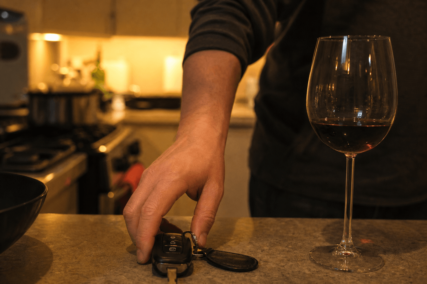 Clés de voiture posées sur une table à côté d'un verre de vin entamé, en fin de soirée