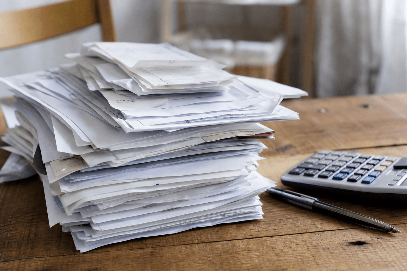Pile de relevés bancaires et documents financiers posés sur une table avec une calculatrice