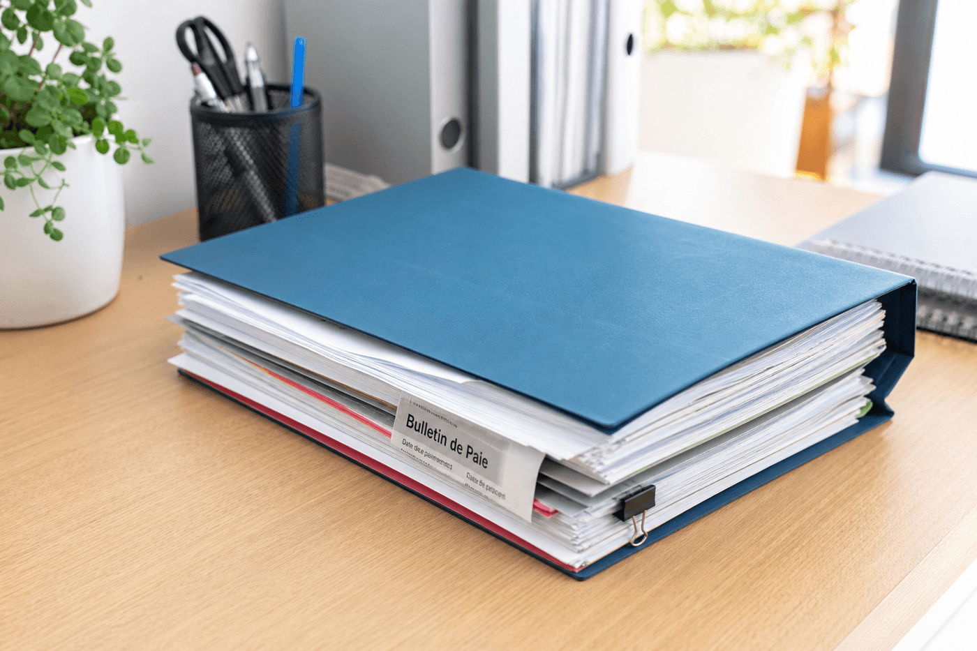 Une pile de fiches de paie et de documents administratifs classés dans un dossier