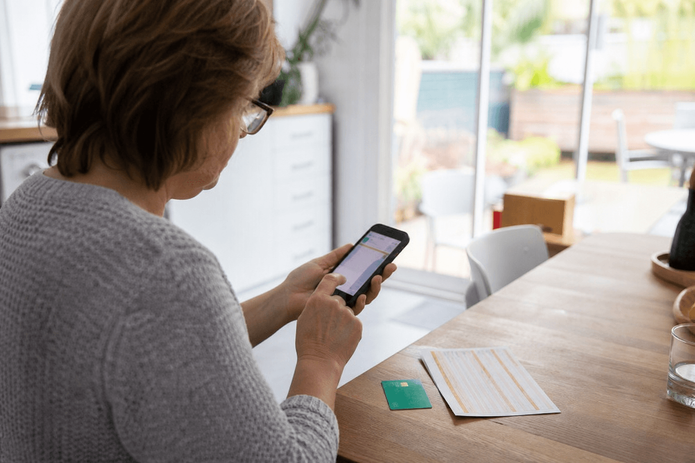 Personne consultant son application de remboursement de santé sur smartphone à côté d'une carte Vitale