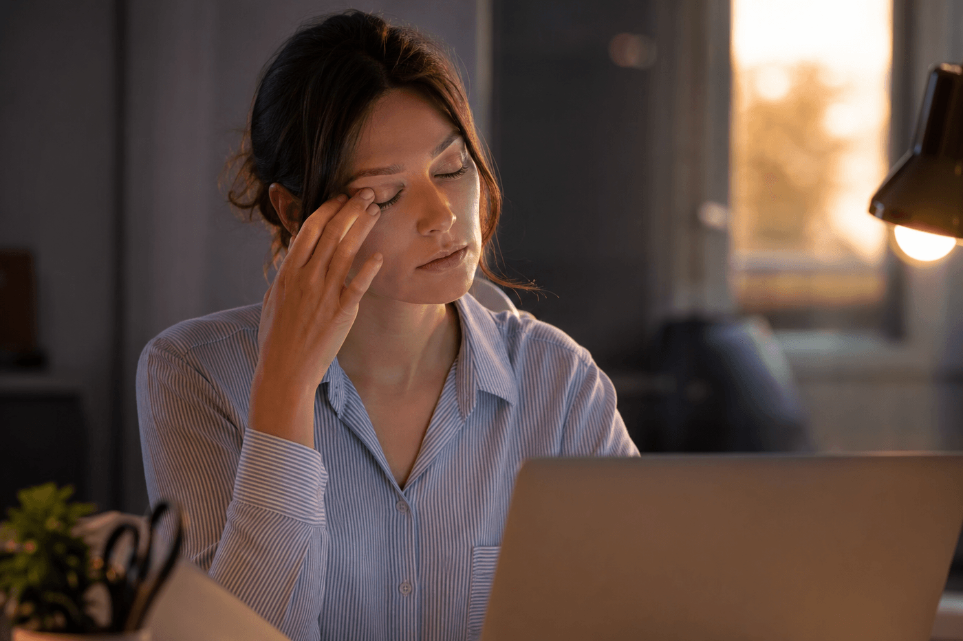 Personne fatiguée se frottant la paupière devant un ordinateur en fin de journée
