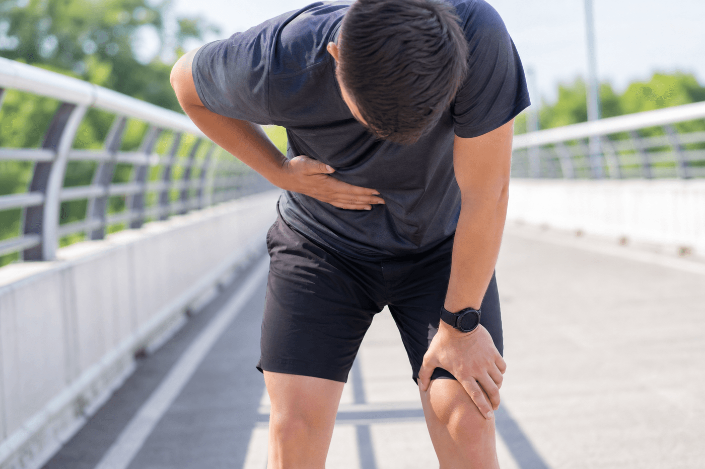 Un coureur en extérieur pose la main sur son flanc à cause d'un point de côté pendant l'effort