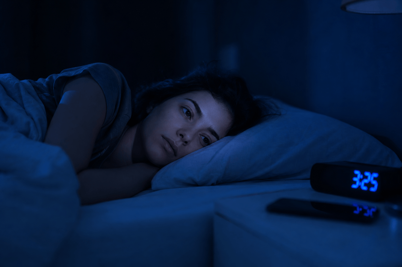 Une personne allongée dans son lit, réveillée en pleine nuit, regardant le plafond