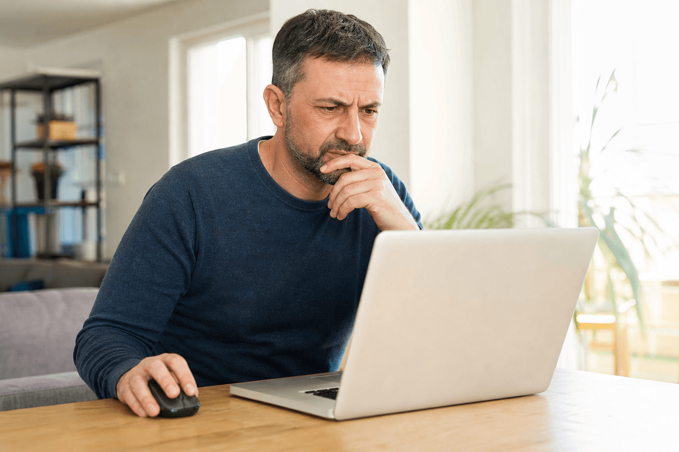 Personne consultant sur son ordinateur portable un email suspect, main sur la souris, prête à vérifier le lien avant de cliquer